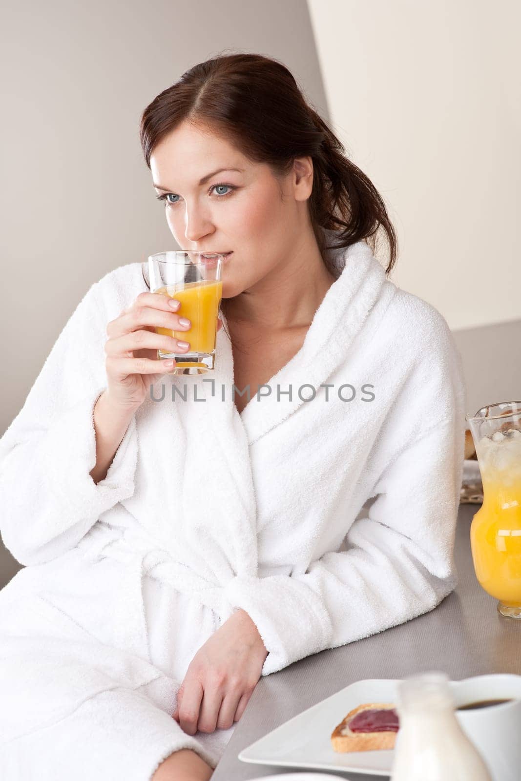 Young woman enjoying orange juice and breakfast in modern kitchen