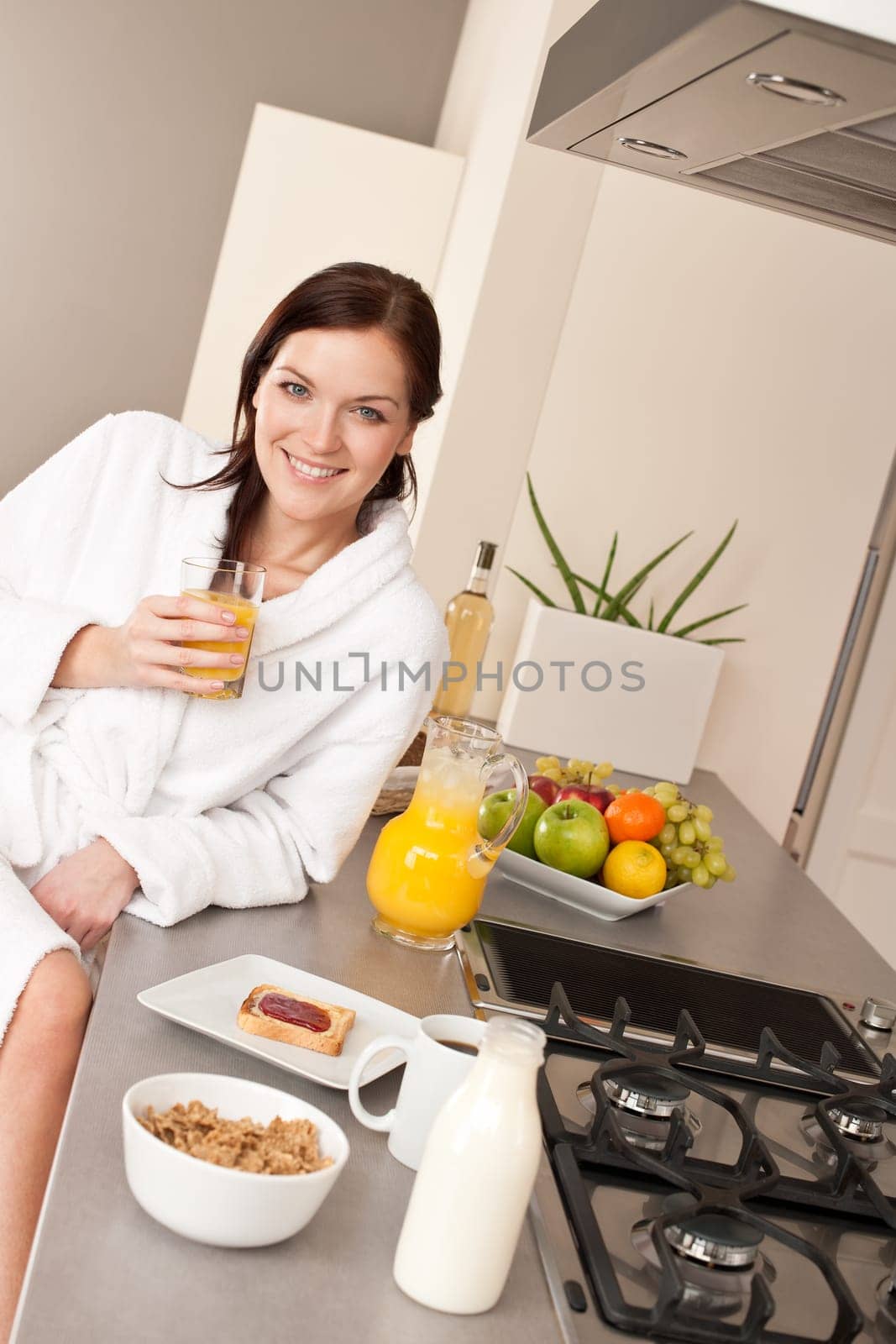 Young woman enjoying orange juice and breakfast in modern kitchen