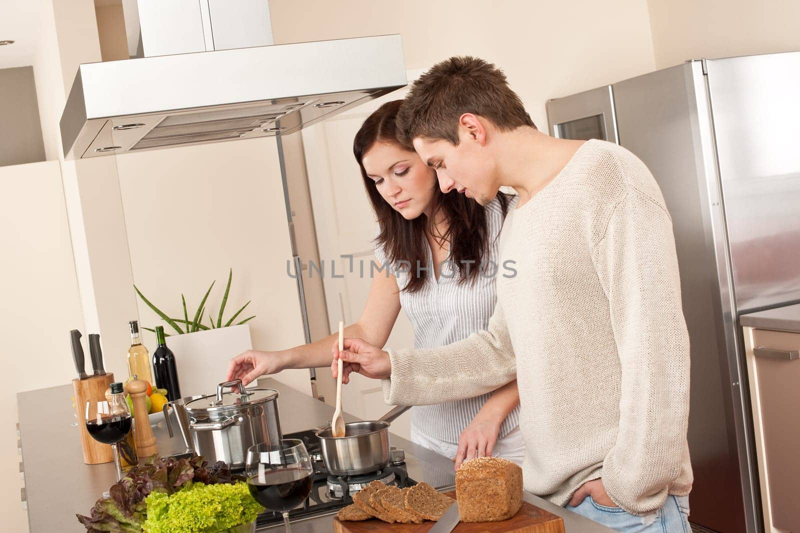 Young couple cooking in kitchen together drinking red wine