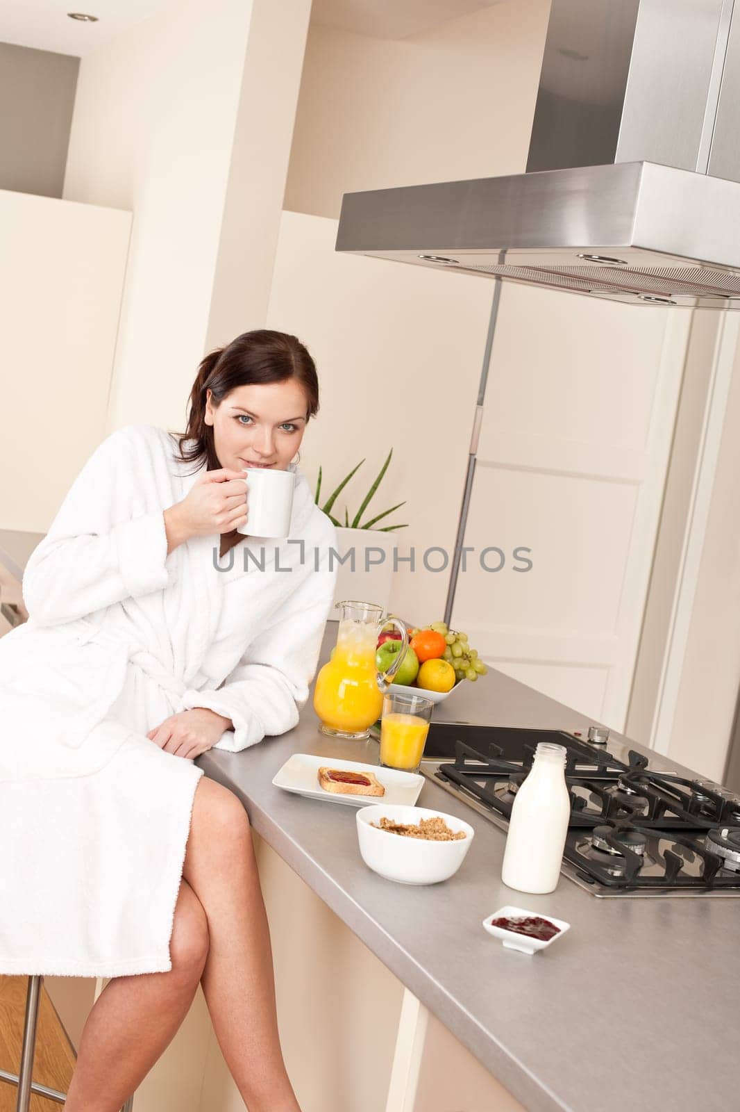 Young woman enjoying coffee and breakfast in modern kitchen