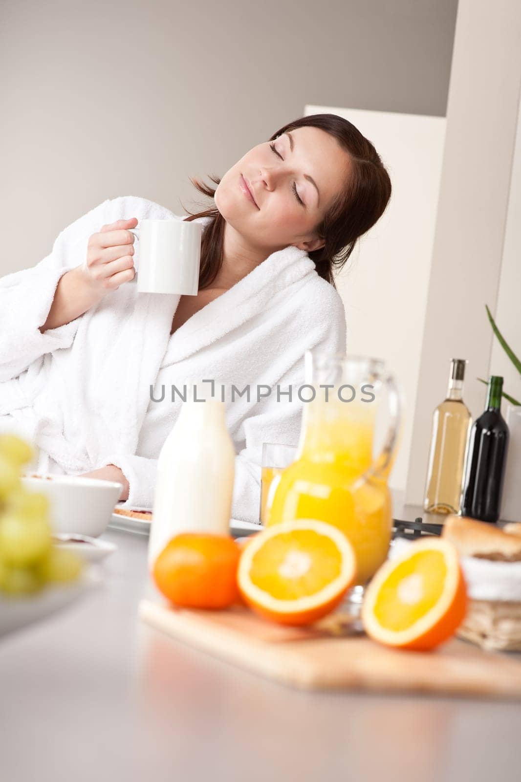 Young woman enjoying coffee and breakfast in modern kitchen