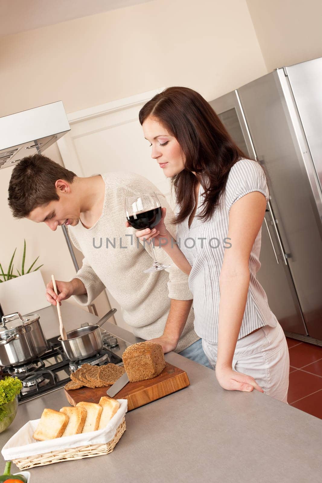 Young couple cooking in kitchen together drinking red wine