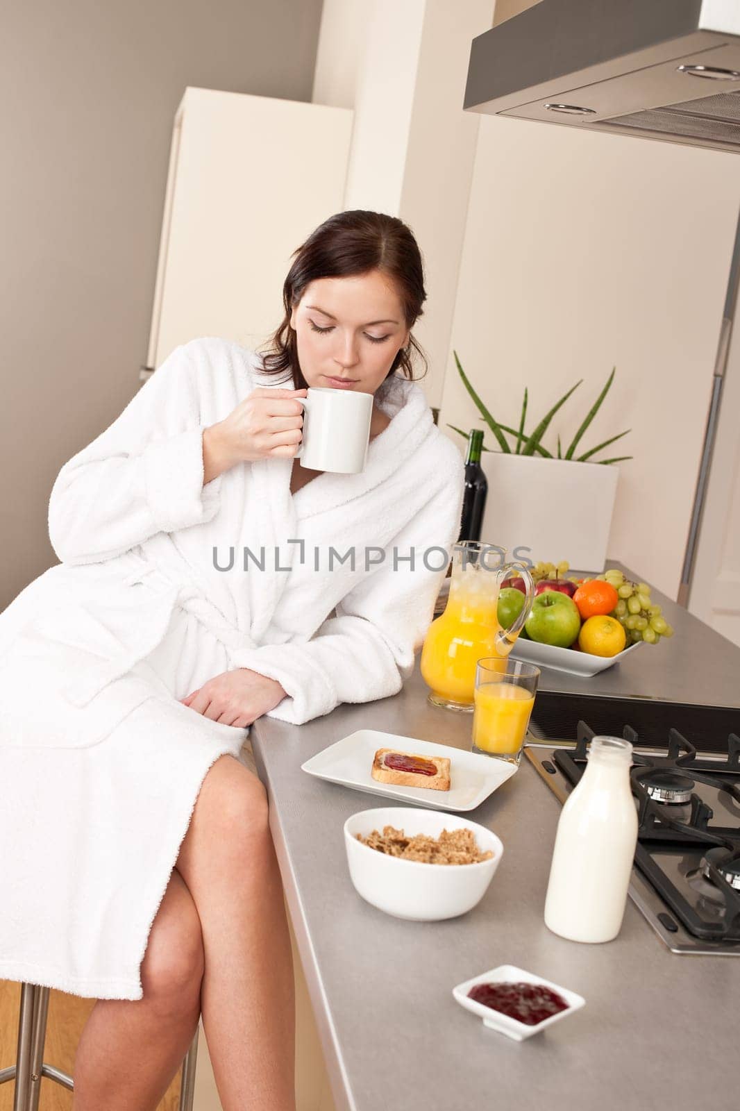 Young woman enjoying coffee and breakfast in modern kitchen