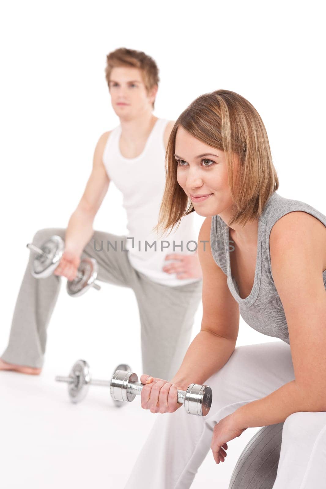 Young healthy couple training with weights and fitness ball on white