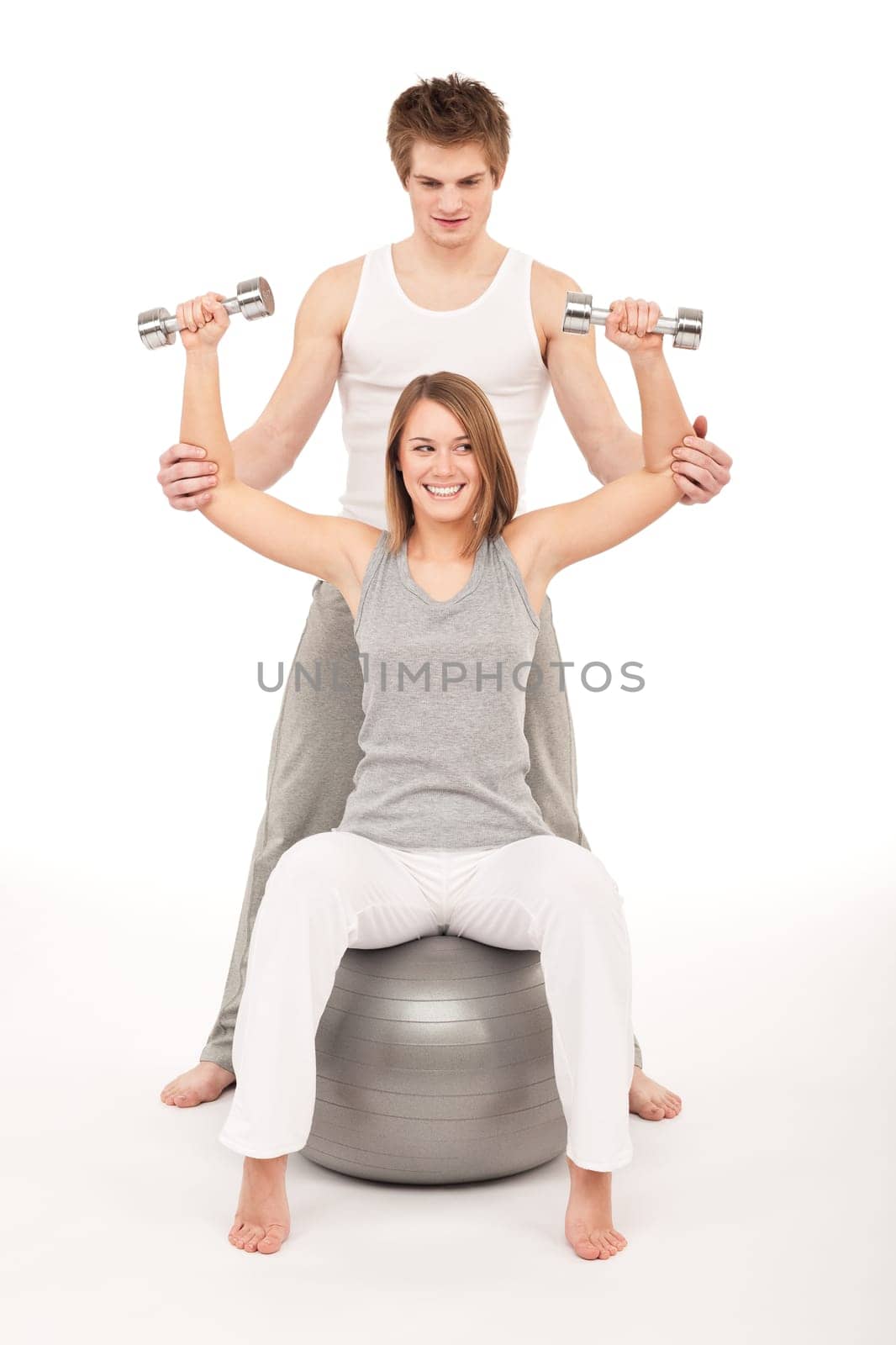 Young healthy couple training with weights and fitness ball on white