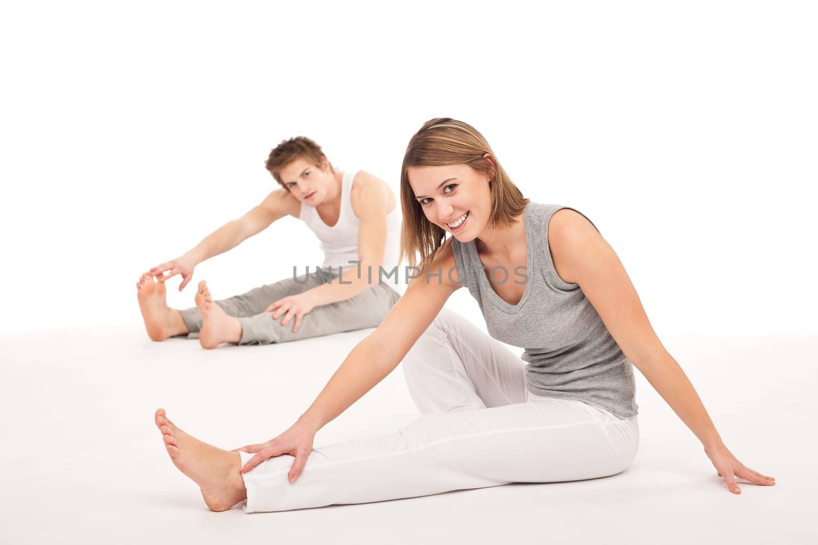 Fitness - Healthy couple stretching after training on white background