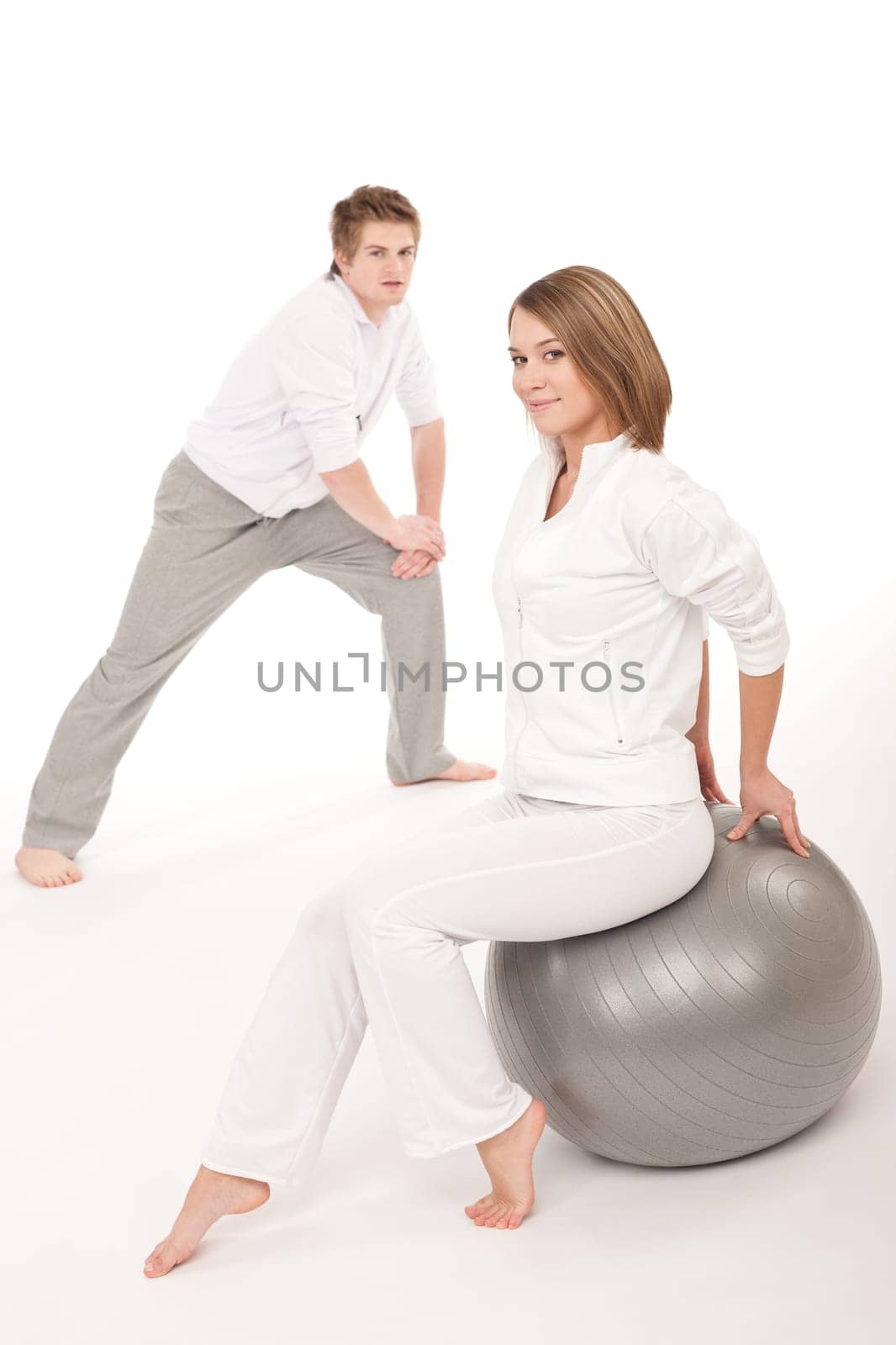 Fitness - Healthy couple stretching after training on white background