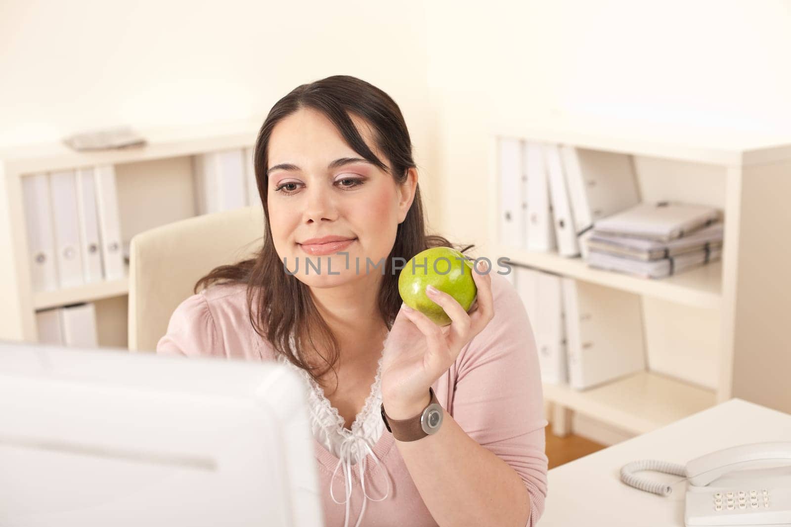 Young happy businesswoman holding apple at office having snack