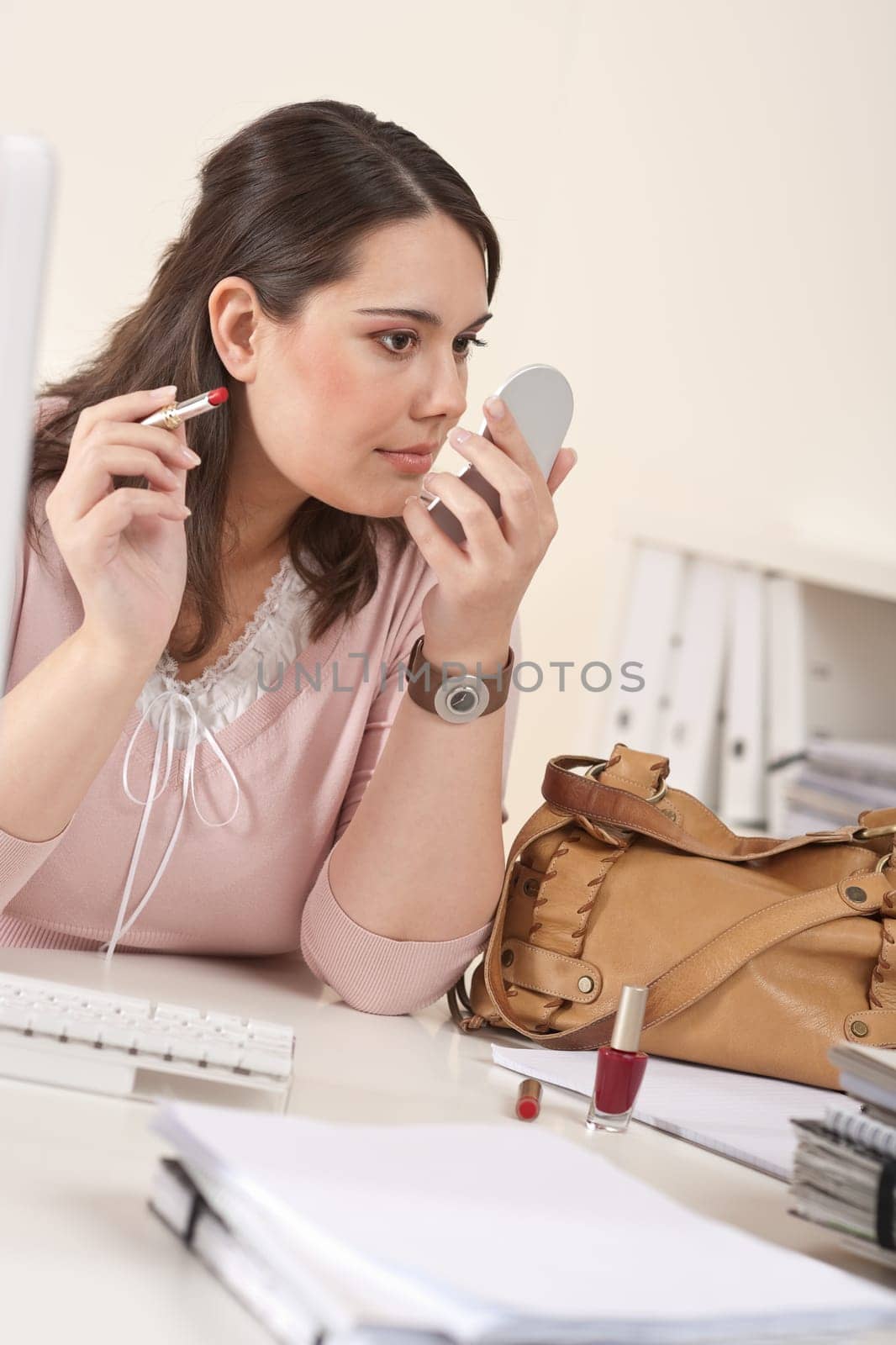 Young executive woman applying lipstick at modern office