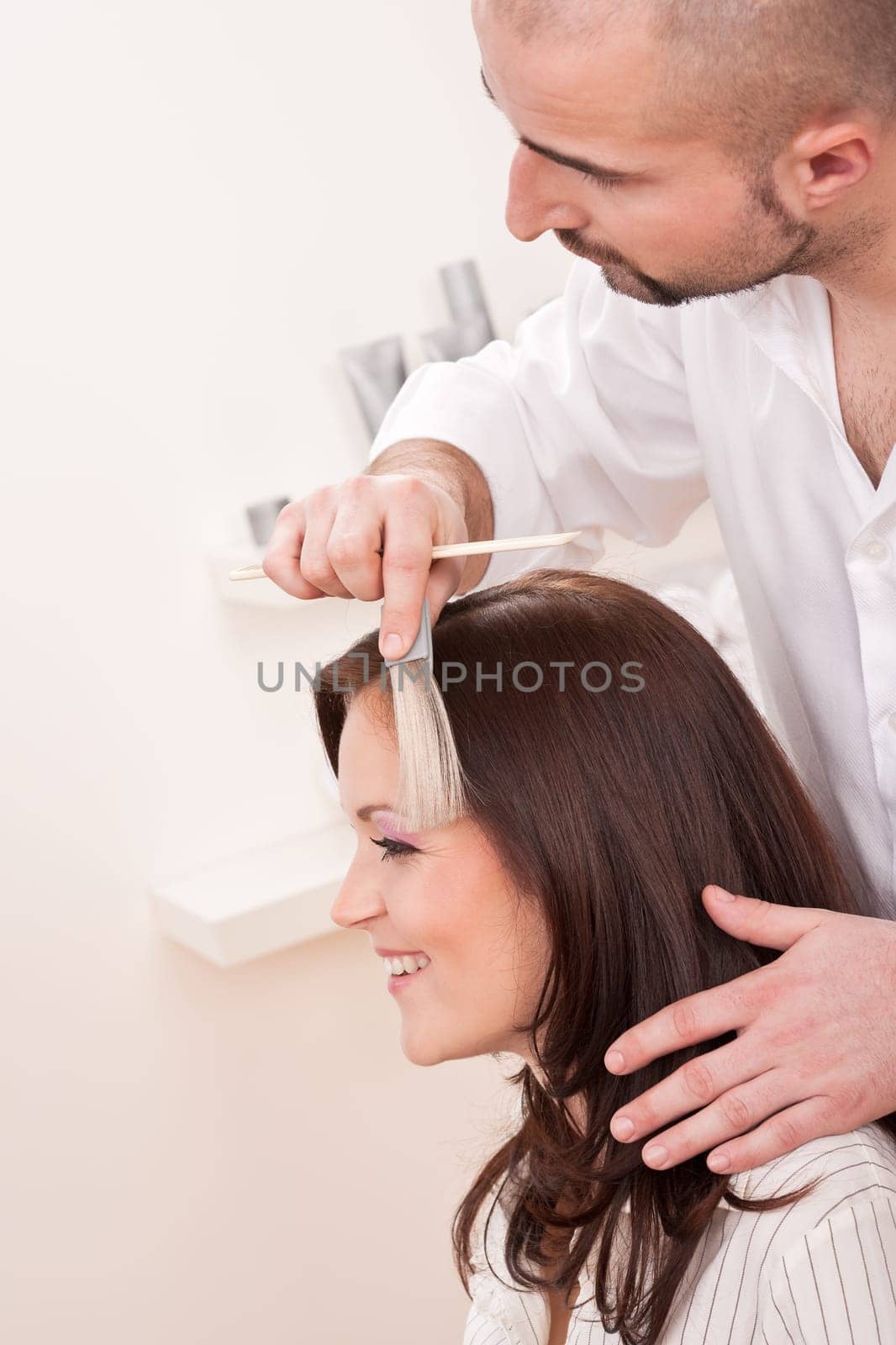 Professional male hairdresser choose hair dye color at modern salon, female customer change hair color