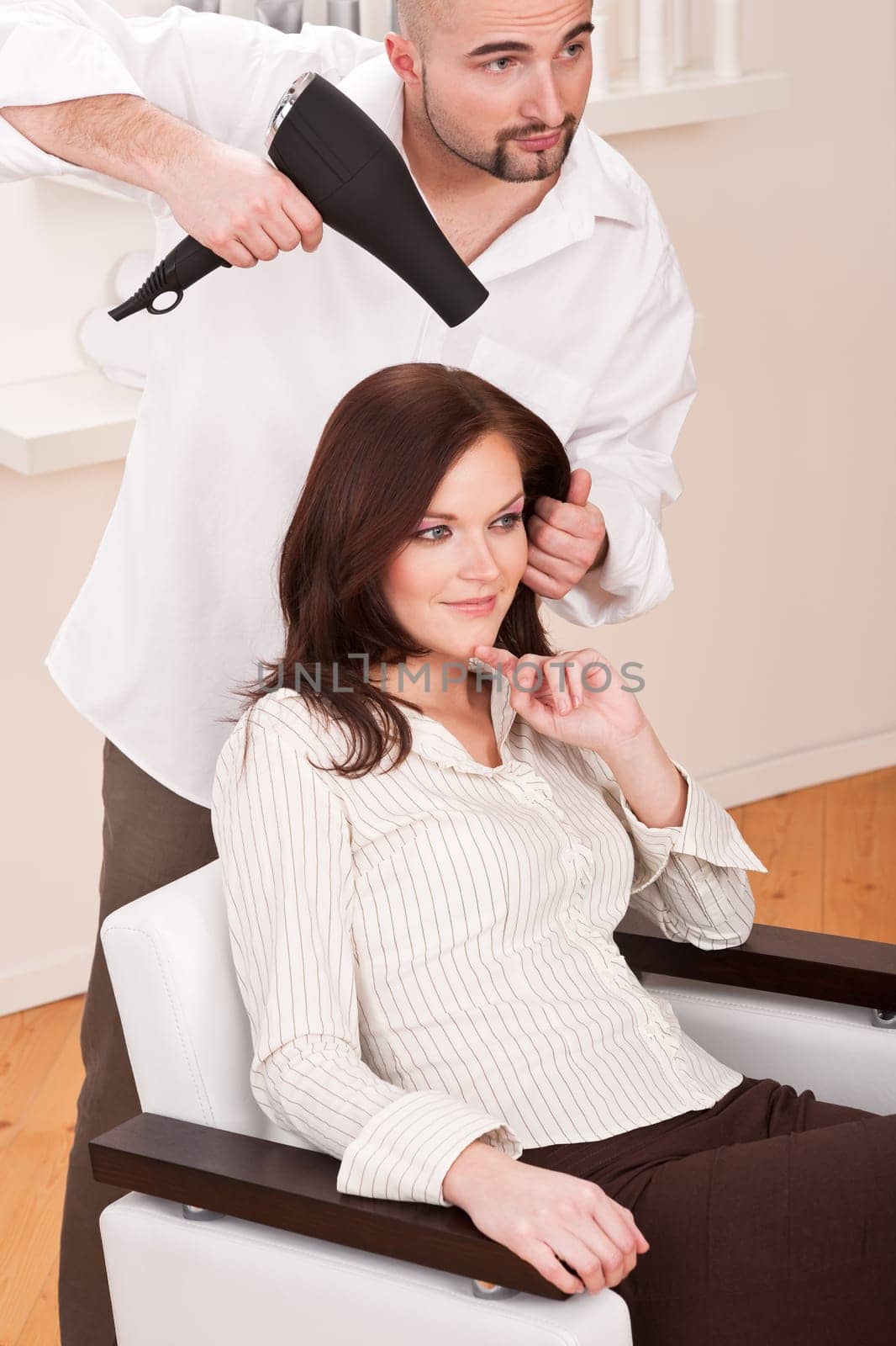 Professional male hairdresser with hair dryer at salon with female customer