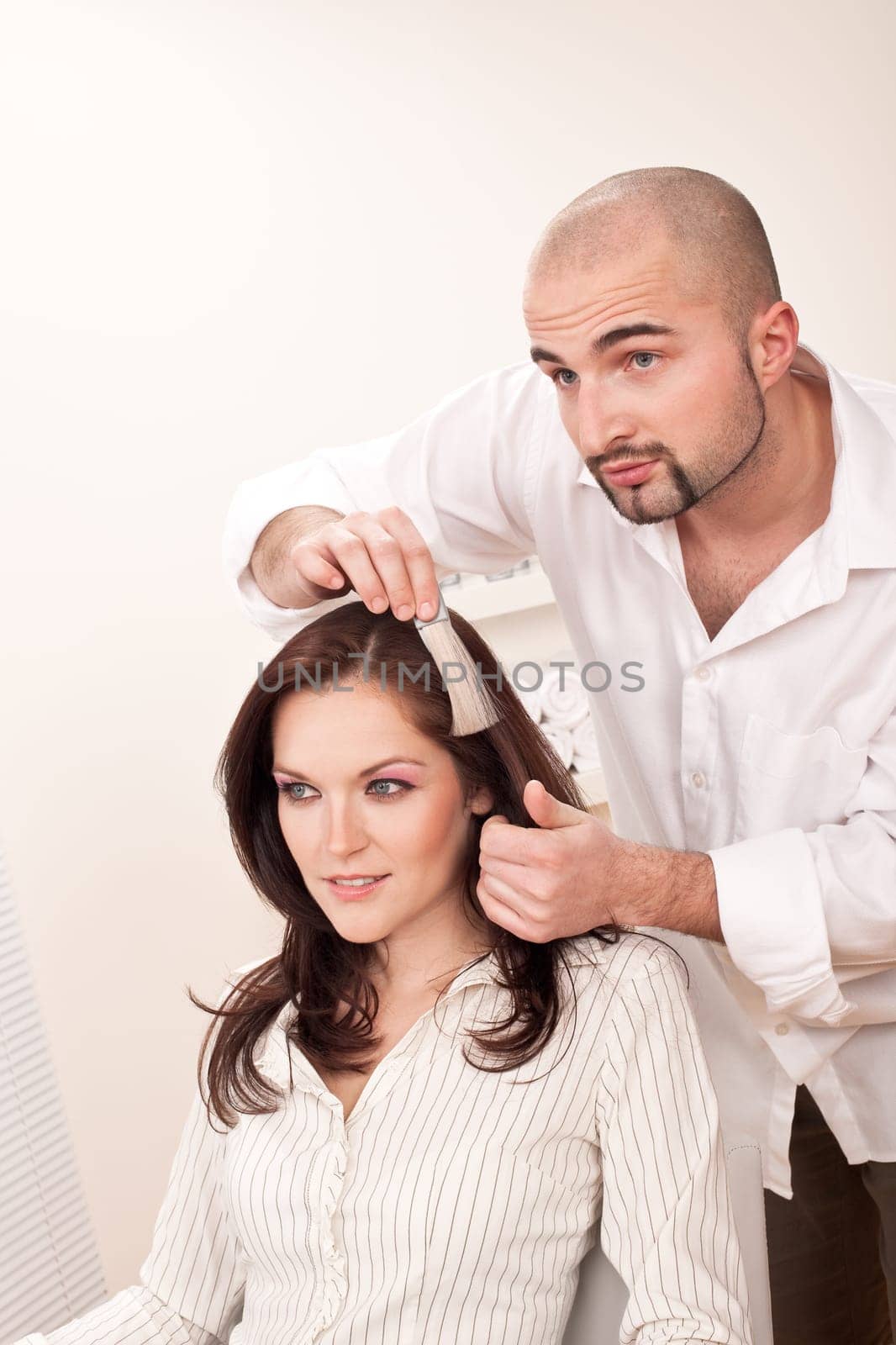 Professional male hairdresser choose hair dye color at modern salon, female customer change hair color