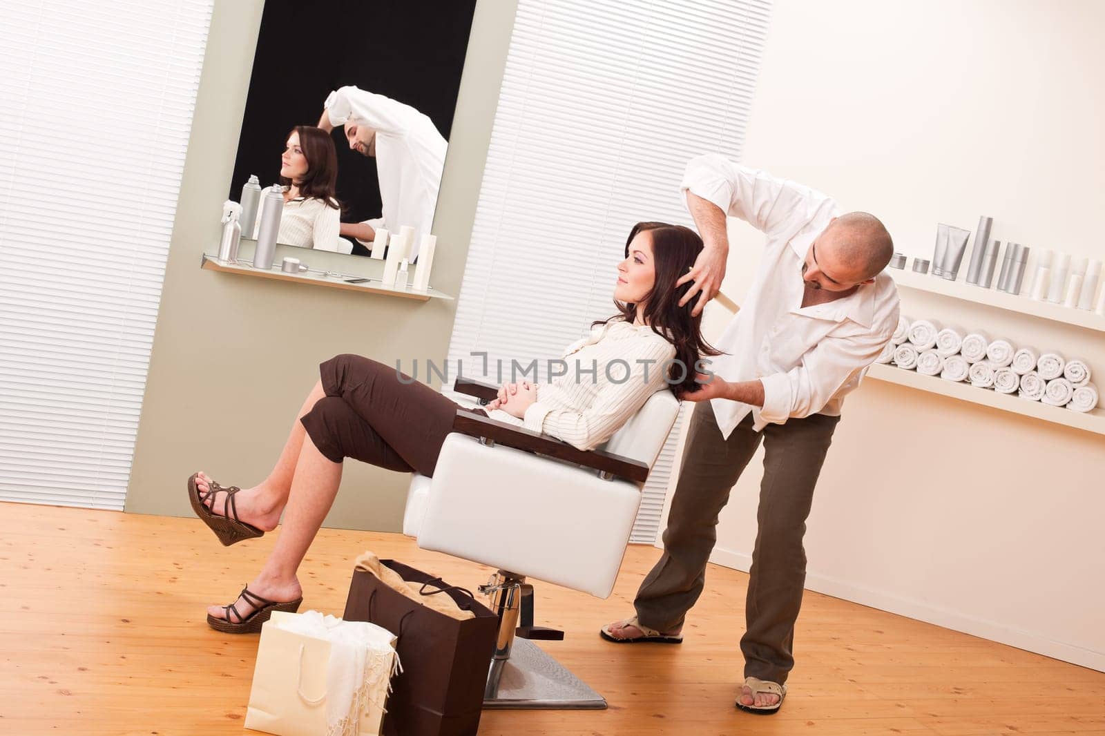 Professional male hairdresser cut with scissors at salon, customer getting new haircut, shopping bags on floor