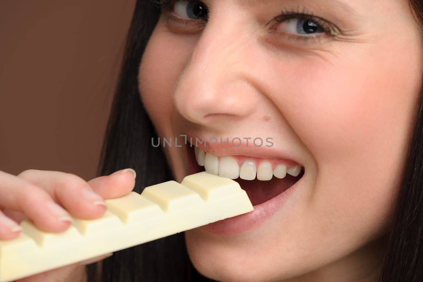 Chocolate - close-up of young woman enjoy sweets on brown background