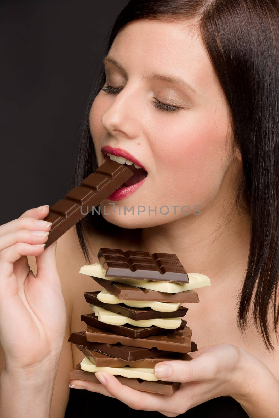 Chocolate - portrait of healthy woman eat sweets on black background