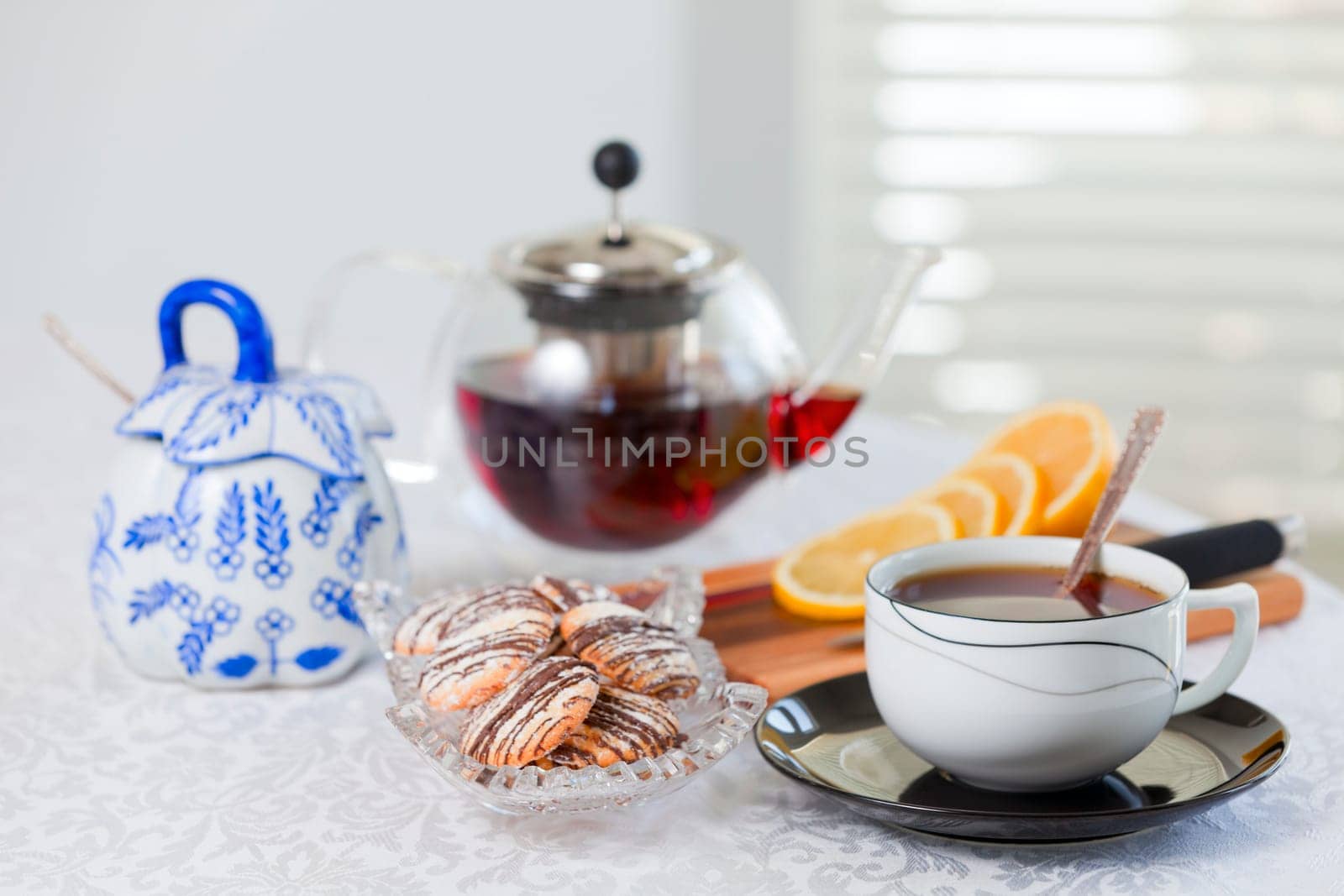 A spread of tea, cookies, and lemon on a white tablecloth