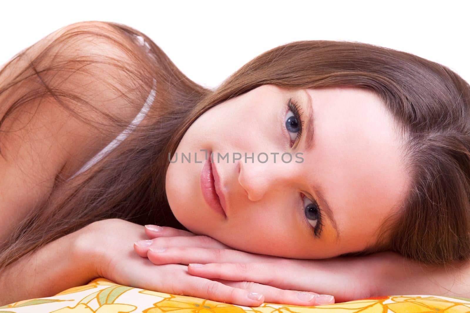 Young woman lay on color pillow slose-up portrait