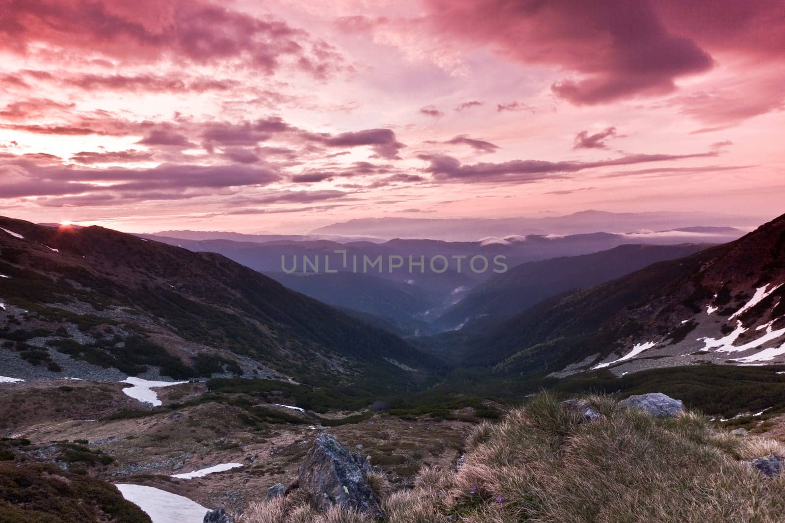 a mountain valley and a red sky with clouds