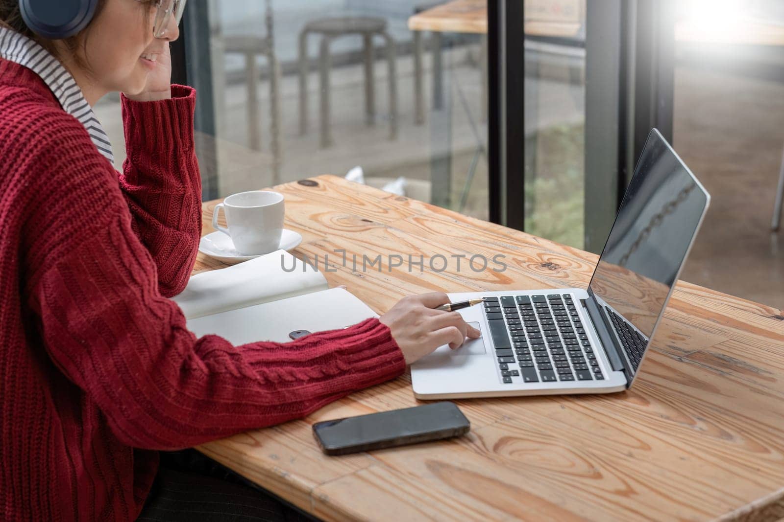 Close-up shot of online studying woman writing notes while sitting in front of her computer laptop at living room. by wichayada