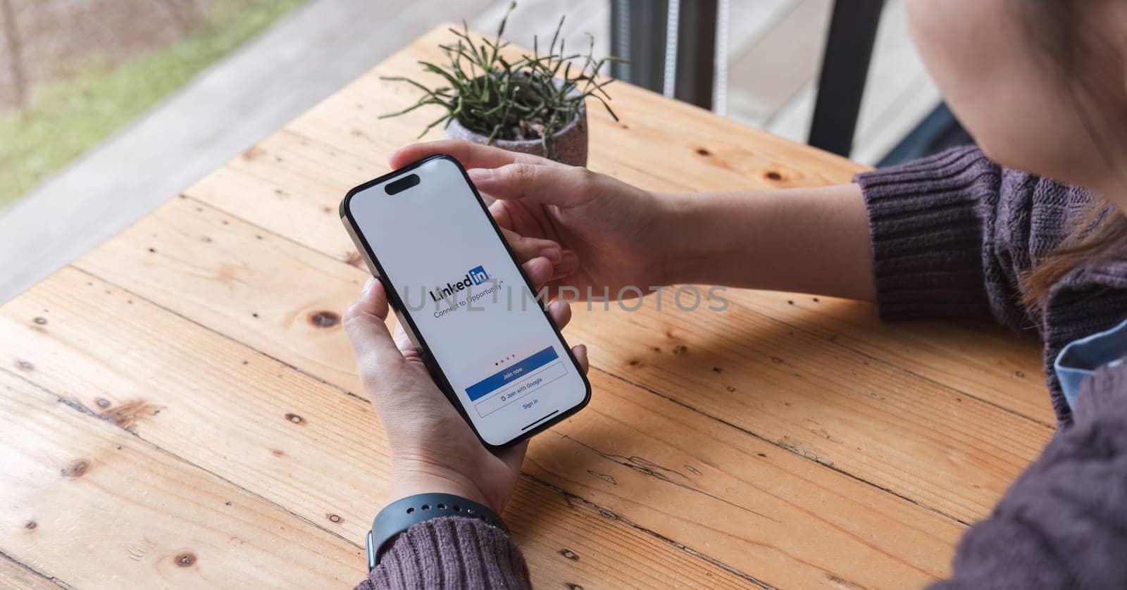 CHIANG MAI, THAILAND, JUL 7, 2023 : A women holds Apple iPhone 14 with LinkedIn application on the screen. LinkedIn is a photo-sharing app for smartphones..