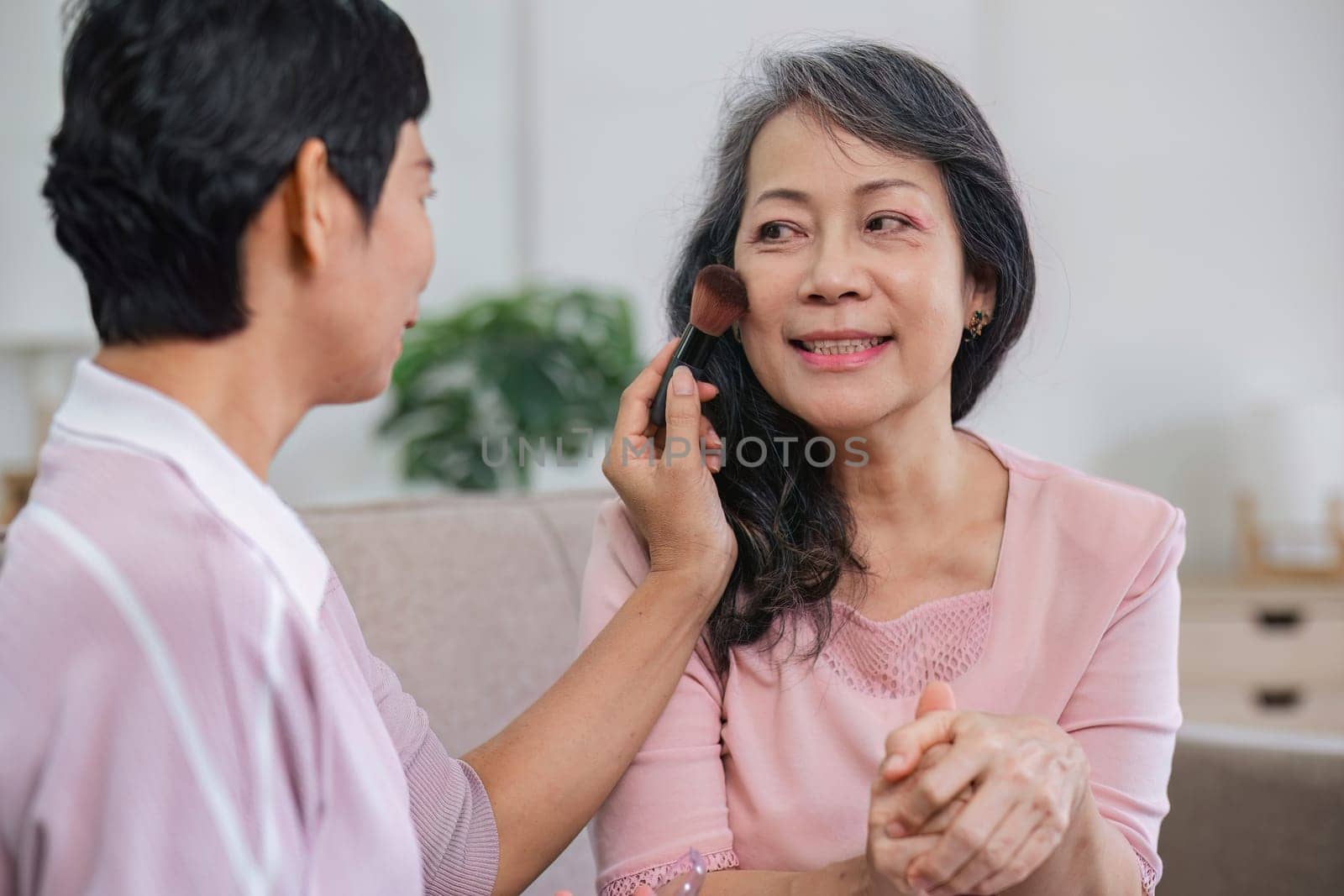 An elderly woman happily spends her free time make up with friends in the living room..