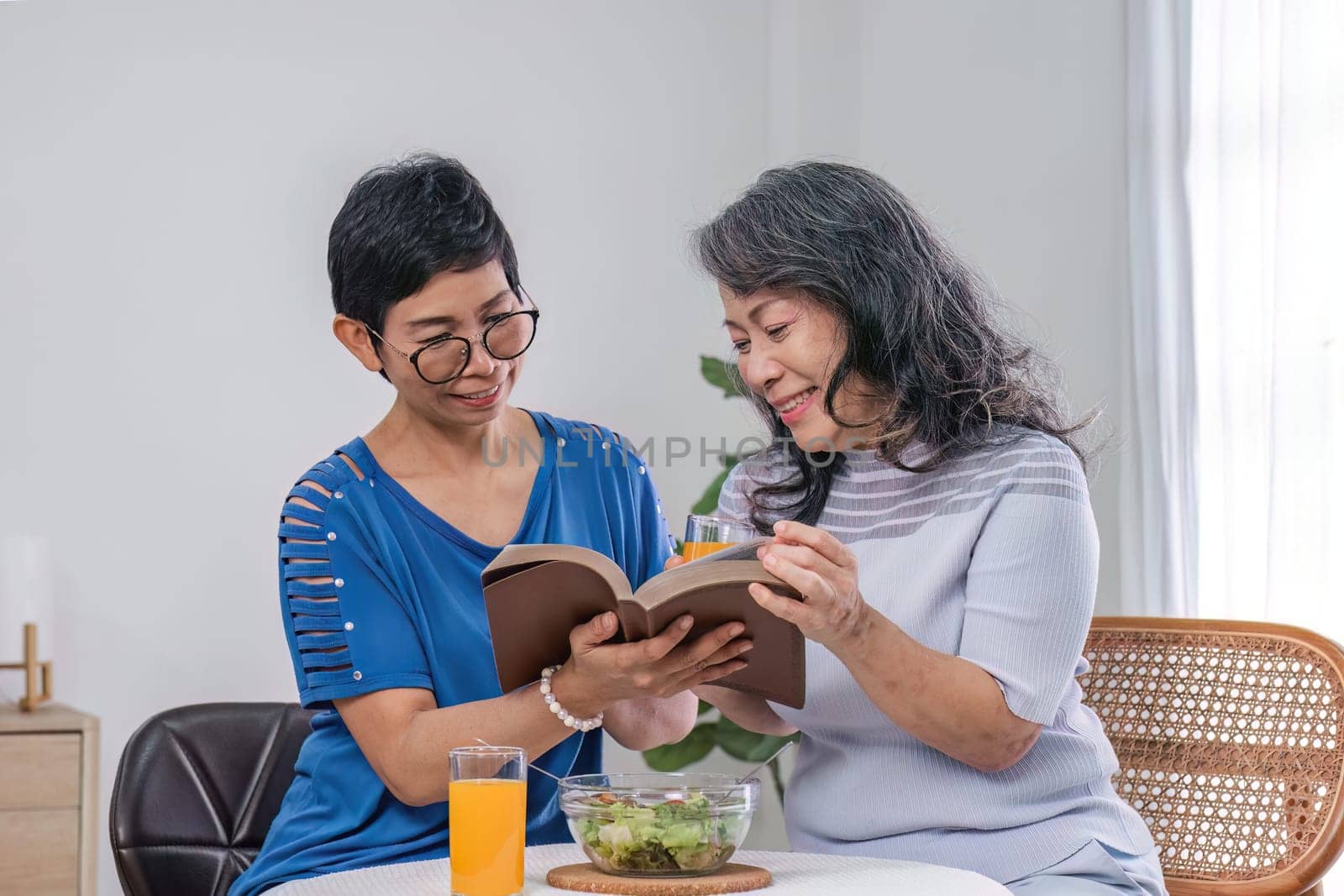 Two 60s woman enjoys talking with her friends and having a healthy food together. by wichayada