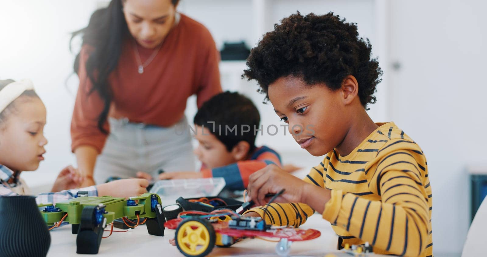 Technology, boy and car robotics at school for learning, education or electronics with car toys for innovation. Classroom, learners and transportation knowledge in science class for research or study.