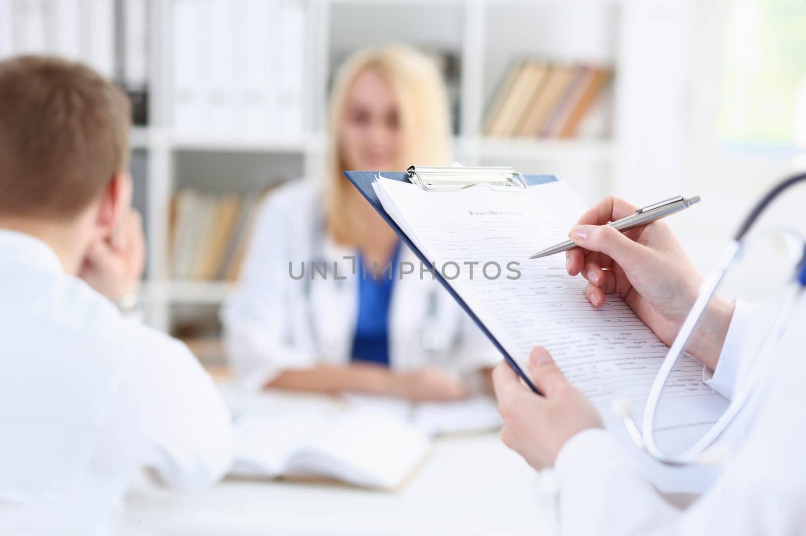 Female medicine doctor hand holding silver pen looking in clipboard pad closeup. Ward round patient visit check 911 medical calculation and statistics concept. Physician ready to examine patient