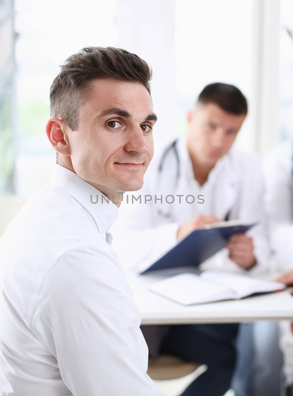 Satisfied happy handsome smiling male patient with doctor at his office. High level and quality medical service therapeutist consultation work and career physical healthy lifestyle concept