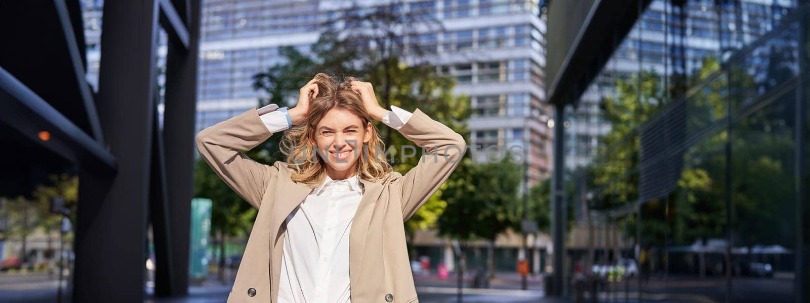 Stylish corporate woman, young lady boss in suit, looking confident and happy, posing outdoors on street. Businesswoman