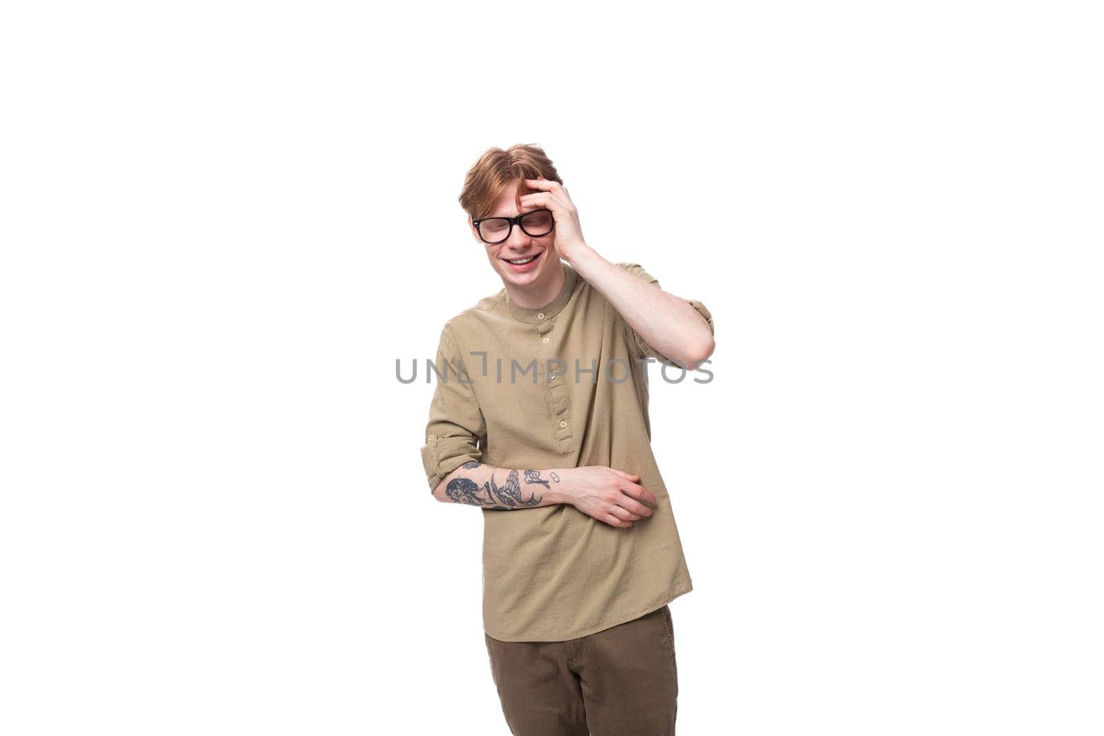surprised young European guy with red hair dressed in a fashionable brown shirt and trousers on a white background. people lifestyle concept by TRMK