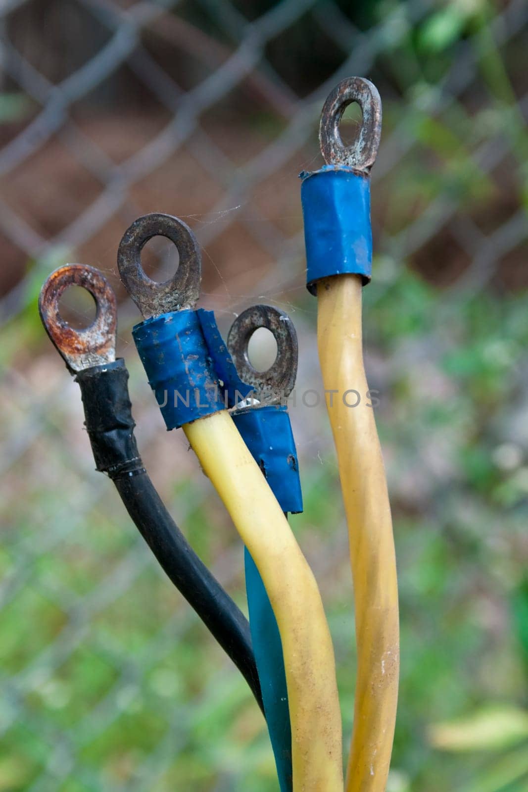bare electricity cable connectors by the roadside, wire fence backdrop