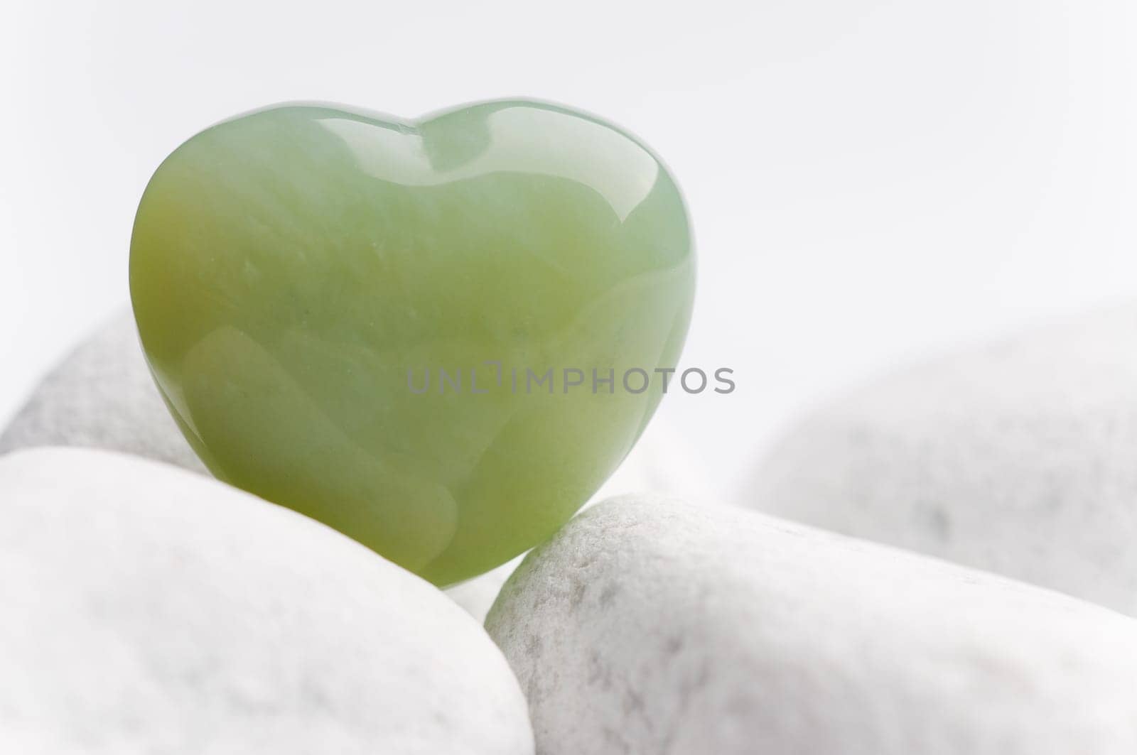 Green quartz mineral heart as a symbol of love on white stones