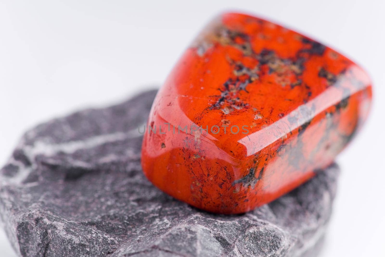 Natural stone red jasper shines in beautiful colors on a white background