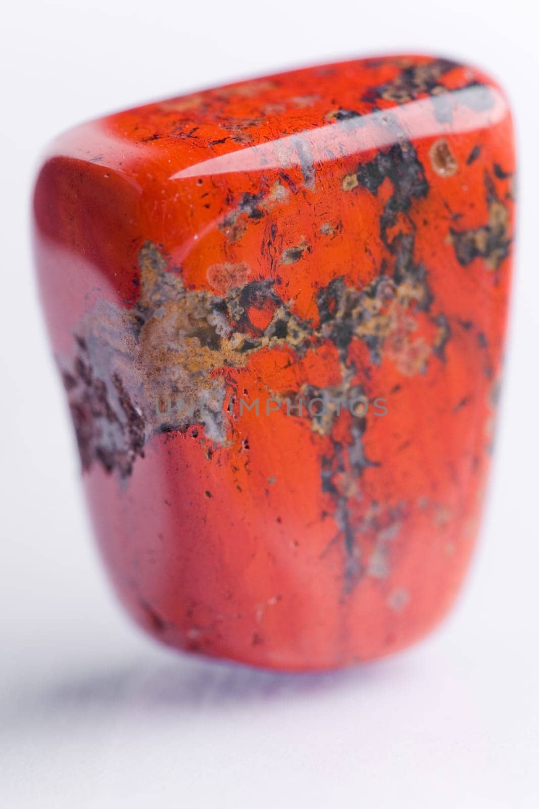 Natural stone red jasper shines in beautiful colors on a white background