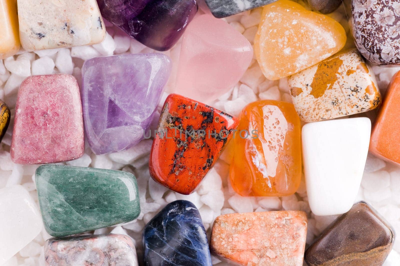 Many different natural stones in beautiful colours on a white background