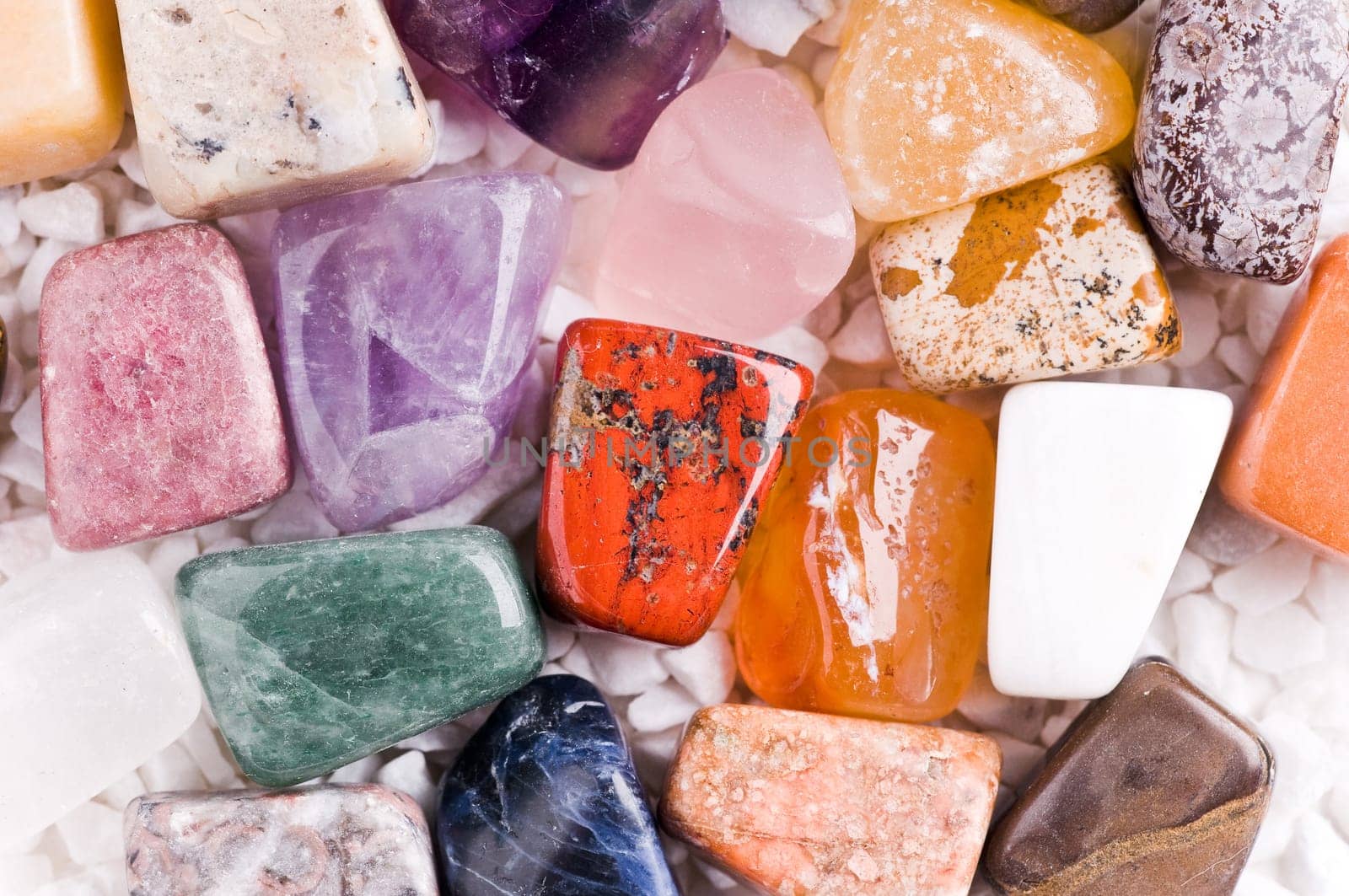 Many different natural stones in beautiful colours on a white background