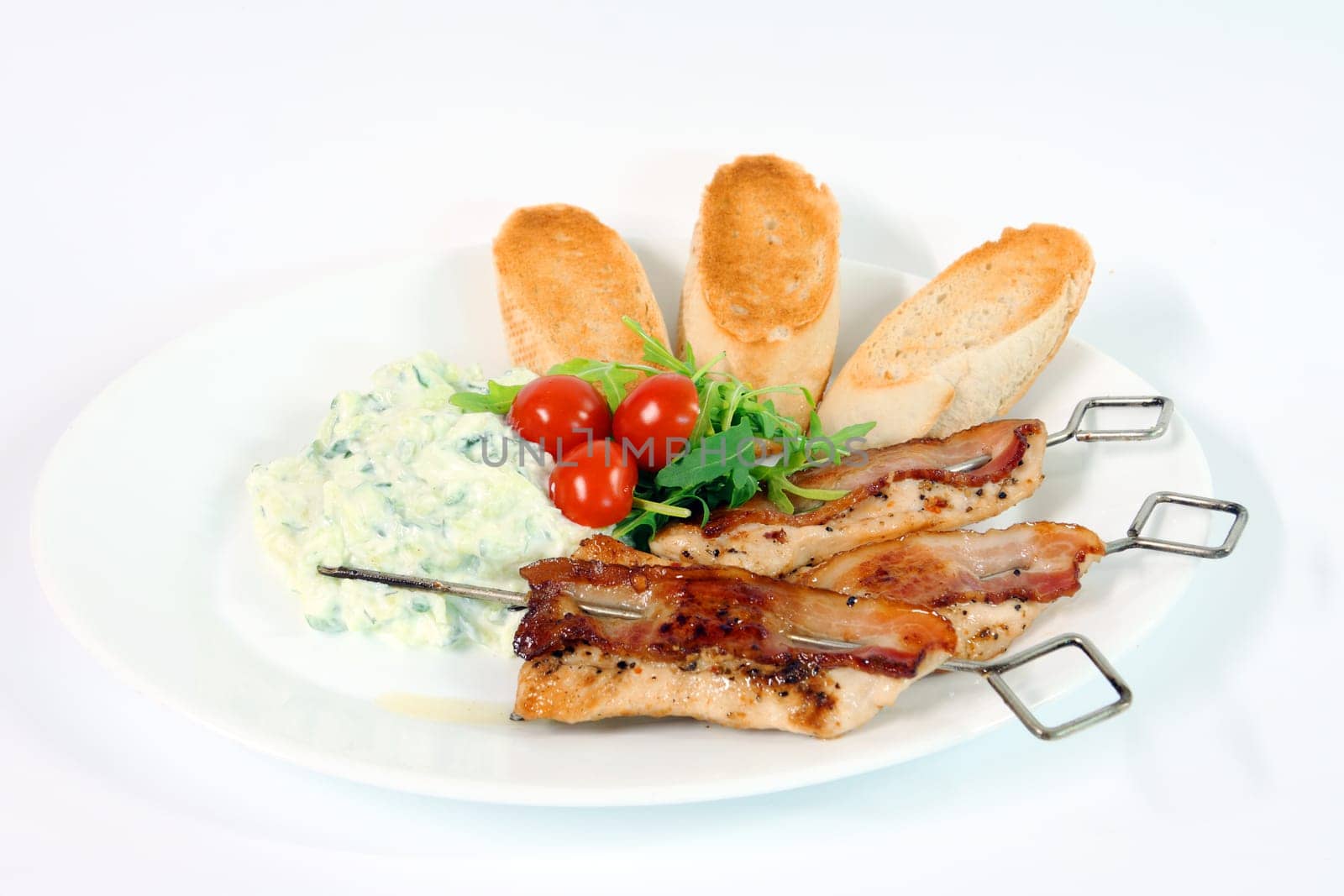 Greek food - tzatziki, chicken souvlaki with bacon and baguette on white background