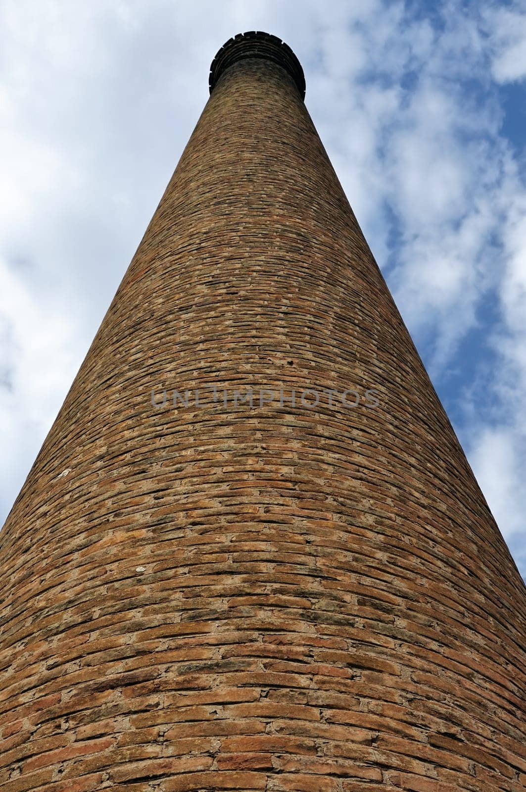 Weathered industrial brick chimney of an abandoned factory.
