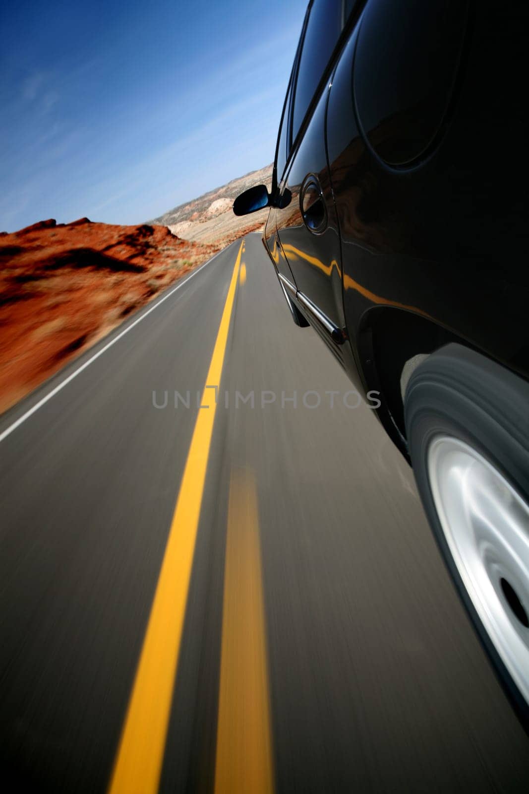 Car driving down rural road in Wyoming. Focus on mirror. Mounted camera, natural motion blur.