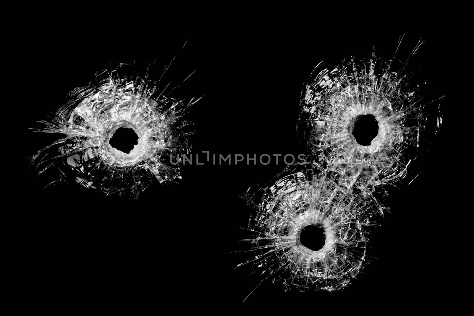 bullet holes in glass isolated on black - bullet holes from .40 handgun closeup
