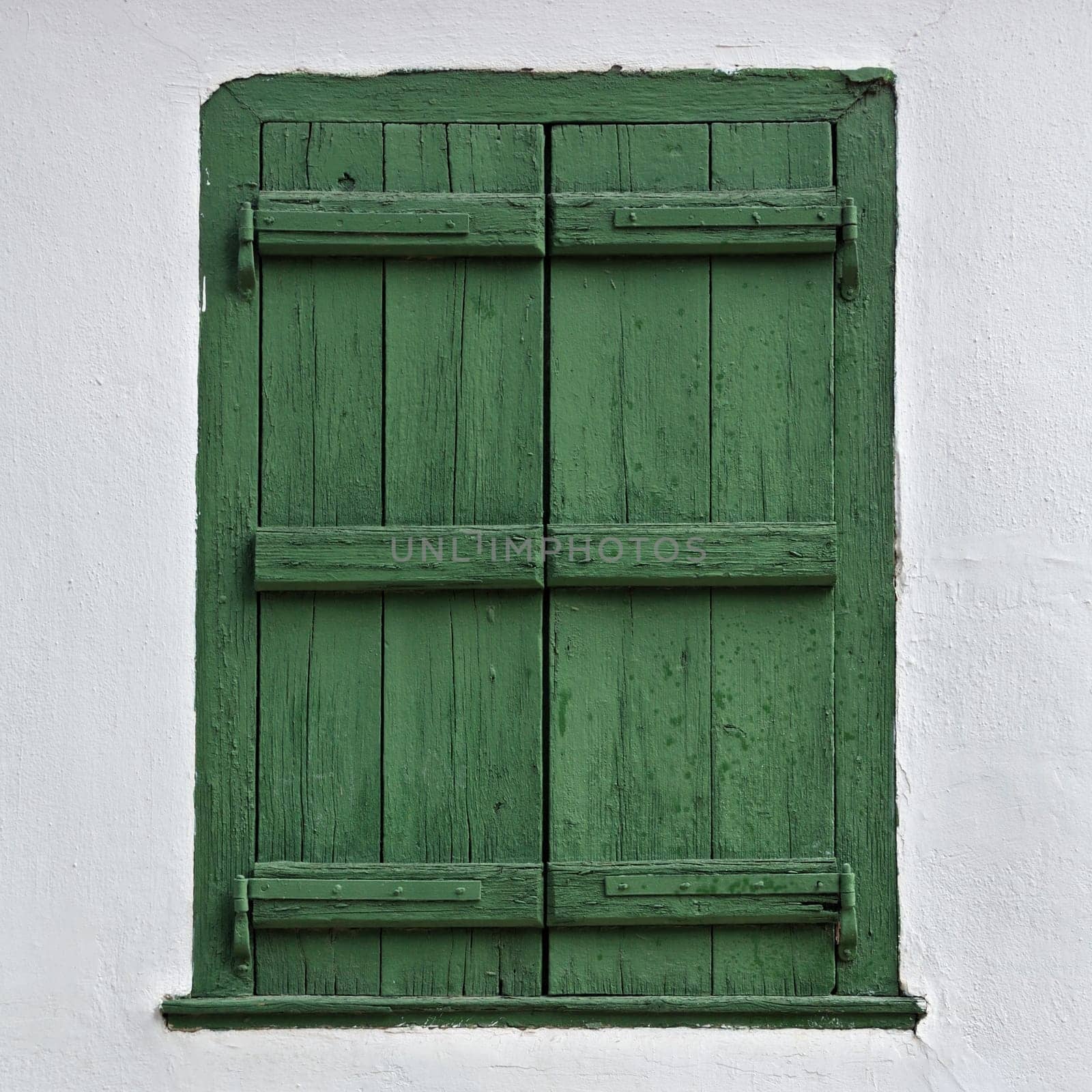 Green wooden window shutter and white wall.