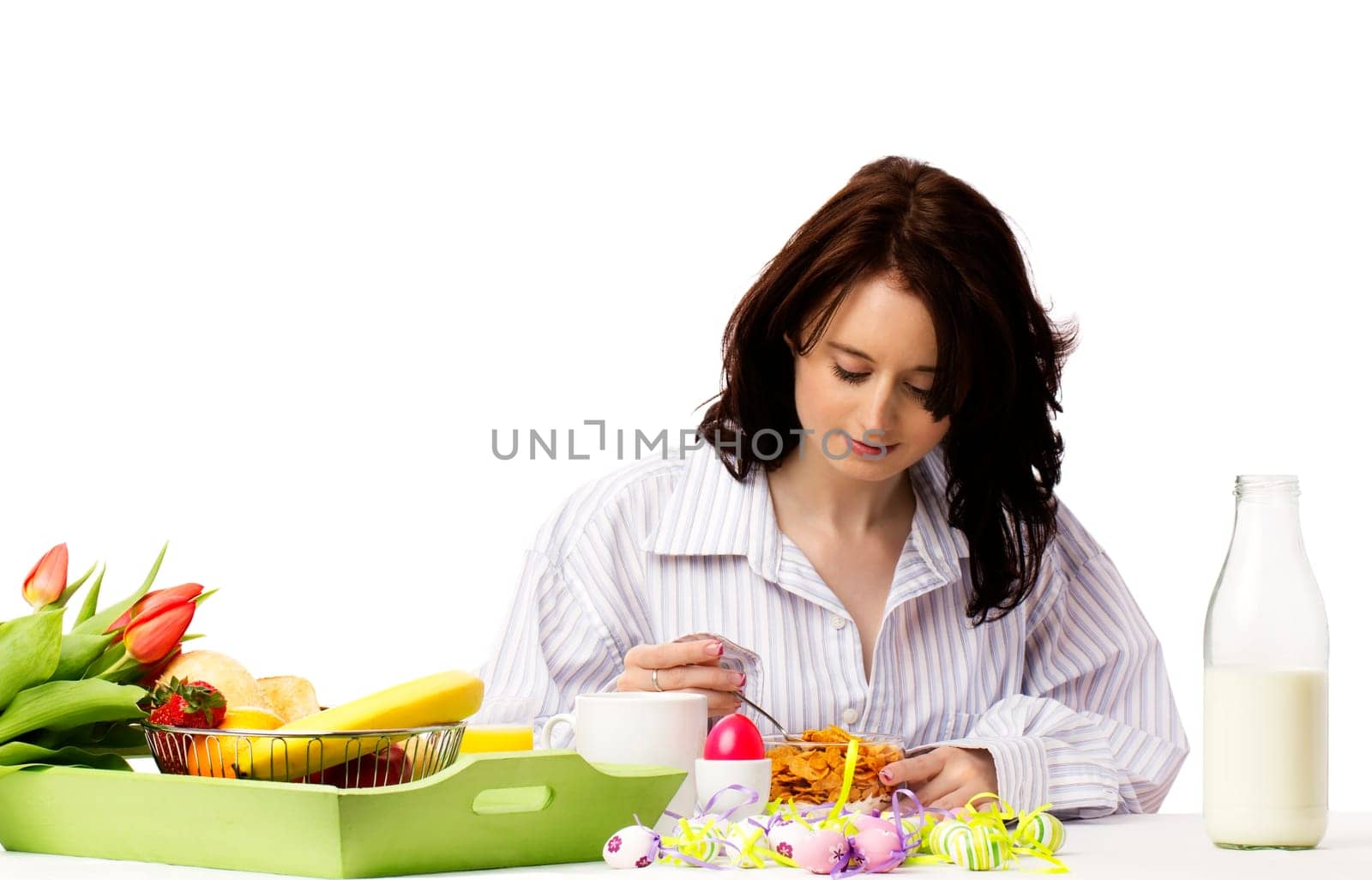 Young pretty woman eating cornflakes at easter breakfast