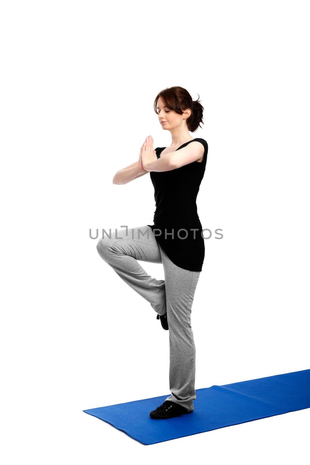 Young woman exercising yoga on one leg and pressing palms together