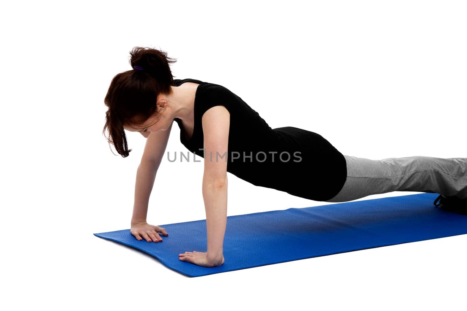 Young woman doing push-ups on a blue yoga mat
