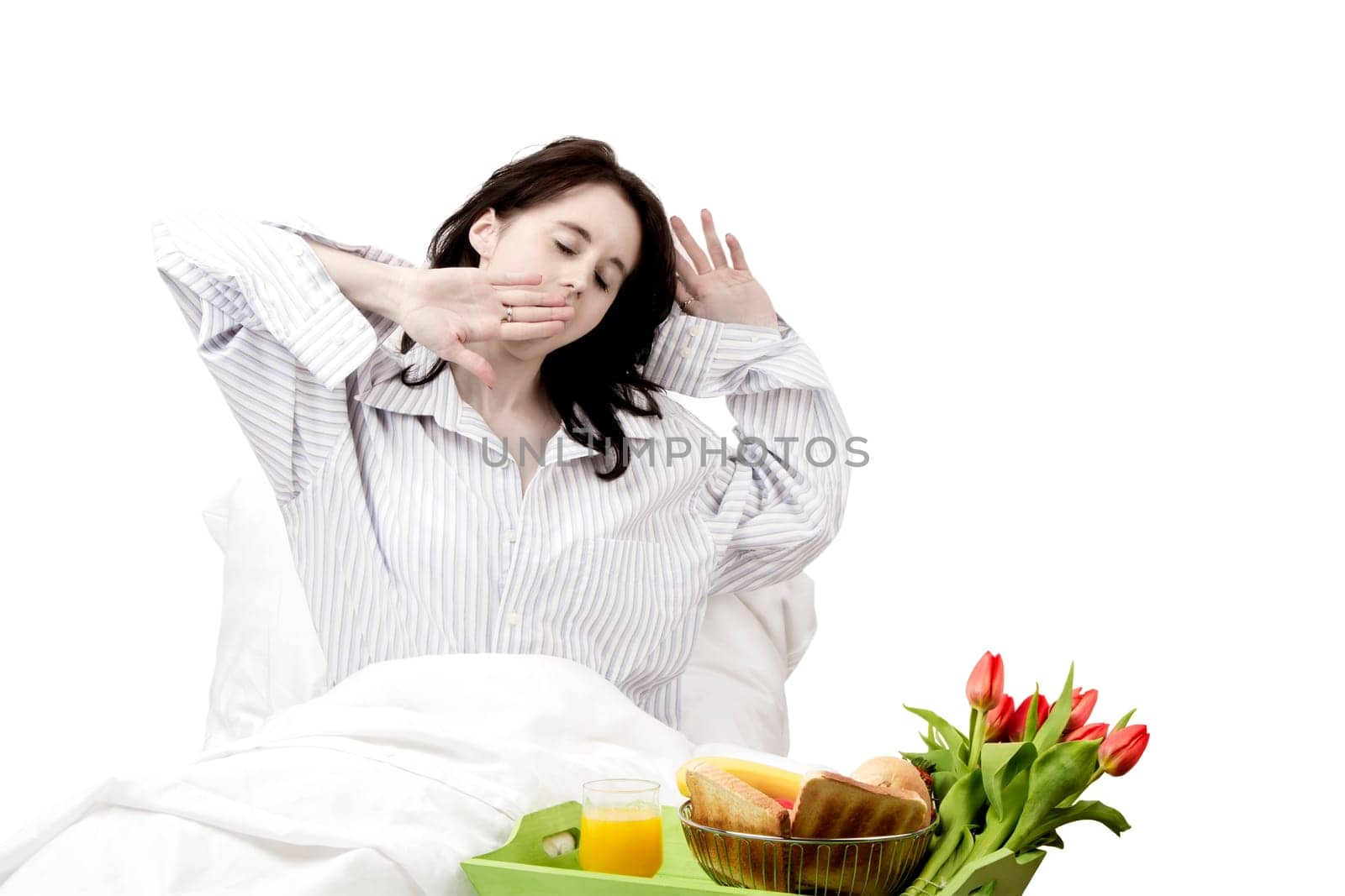 Young woman yawning at breakfast in bed