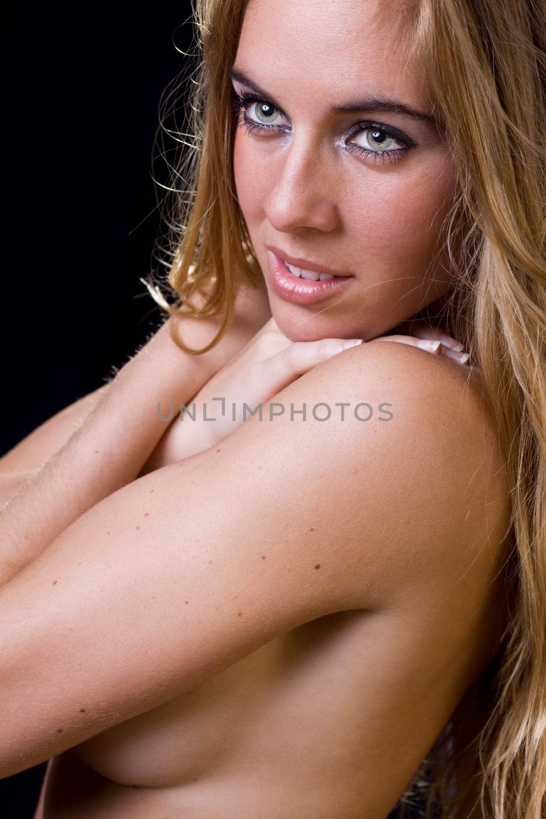 sensual and elegant image of a gorgeous young blond girl covering her breast with the arms