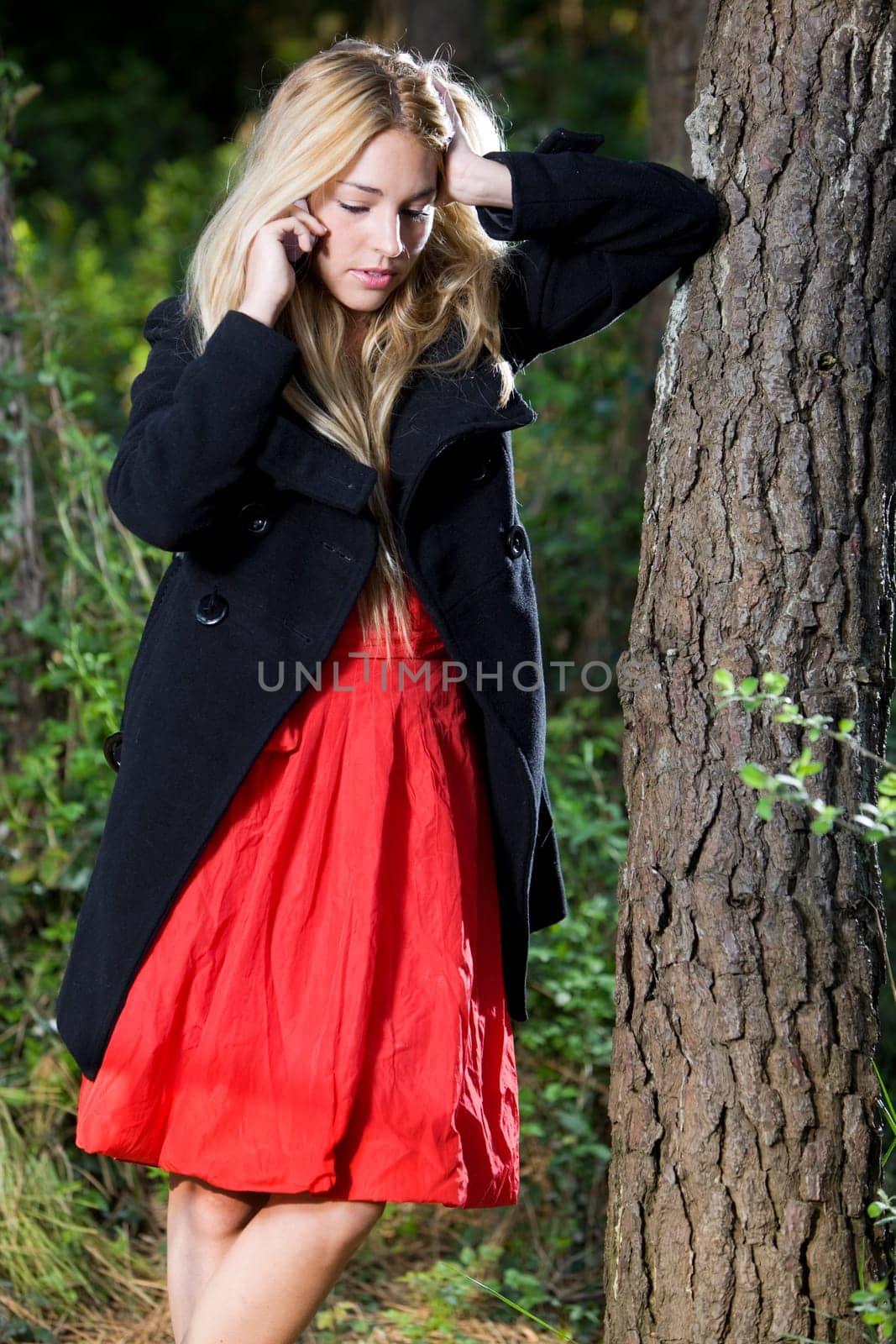 a young beautiful real girl talking with her mobile phone in the nature