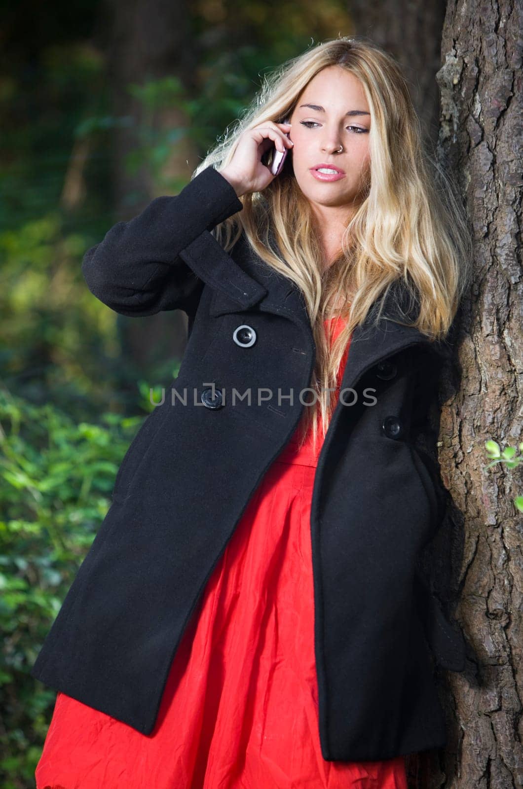 a young beautiful real girl talking with her mobile phone in the nature