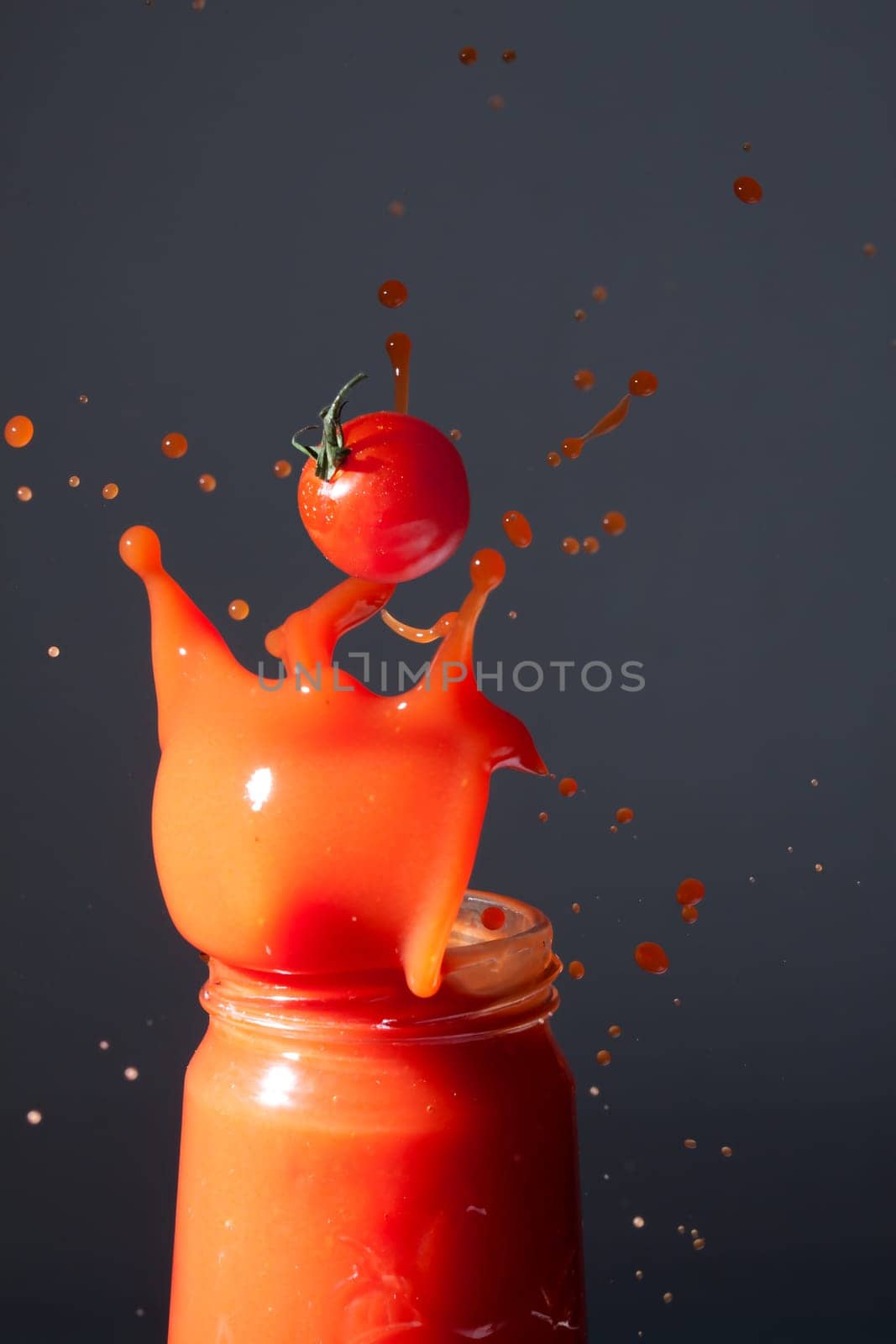 Tomatoes fall into a bottle of tomato juice